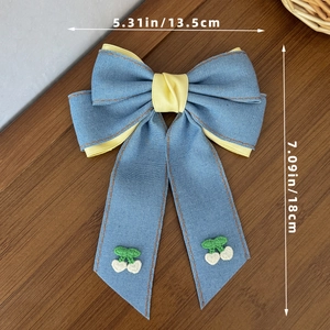 Dettaglio del fiocco per capelli in denim con ricamo a ciliegia e misura 13,5x18 cm