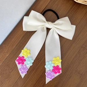 Détail du nœud de cheveux en satin crème avec fleurs brodées colorées sur les rubans