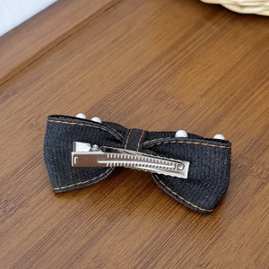 Barrette à nœud en jean avec perles blanches et surpiqûres orange sur bois chaud