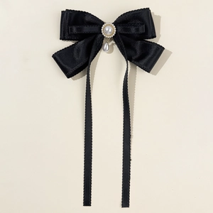 Detail of elegant black satin bow hair clip with faux pearl and tassel ribbon decor