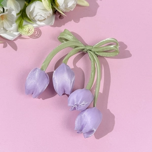 Dettaglio del fermaglio per capelli a tulipano in raso viola con fiocco in nastro verde
