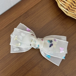 Detailed macro view of white mesh lace bow hair clip with colorful butterfly patterns