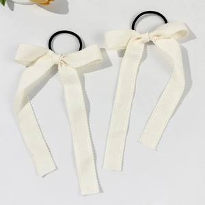 Close-up of cream lace bow hair ties with long ribbons and black elastic bands