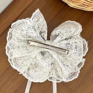 Barrette nœud en dentelle blanche avec rubans élégants sur fond bois sombre