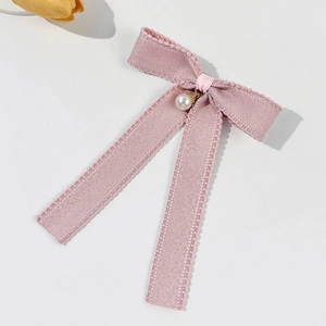 Detailed macro of pink bow hair clip with white pearl pendant and lace edges