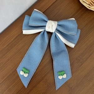 Dettaglio di fermaglio per capelli a fiocco in denim con ricamo a ciliegia su legno