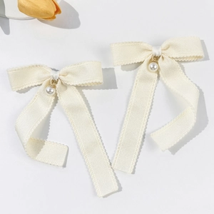 Detail of cream bow hair clips with faux pearl charms and textured ribbon finish