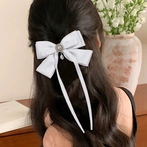 Elegant white ribbon bow hair clip with pearl tassels for women shown on a model