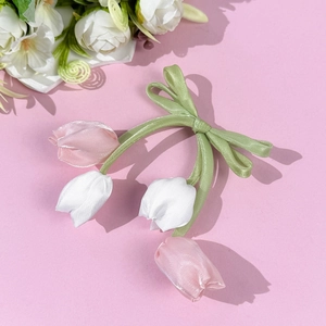 Dettaglio di tulipani in tessuto fatti a mano e fiocco in nastro di raso verde per capelli