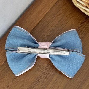 Haarklammer aus Jeansstoff mit rosa Schleife und Kirsch-Herz-Details auf Holzgrund