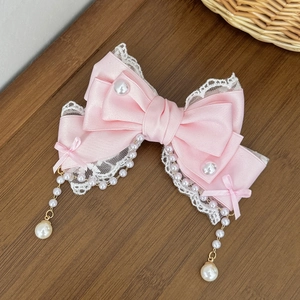 Détail de la pince à cheveux Lolita en satin rose avec dentelle et glands de perles