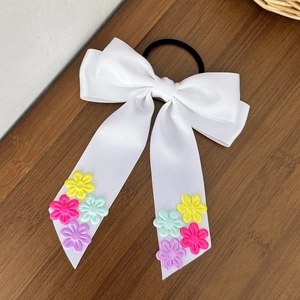 Détail du chouchou en satin blanc avec fleurs 3D colorées et long ruban élégant