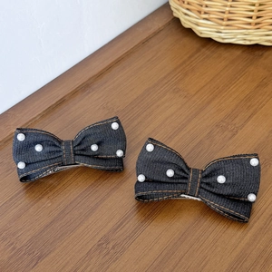 Détail de barrettes à nœuds en denim bleu foncé avec perles blanches et coutures