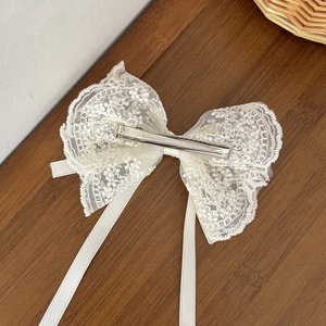 Elegante fermaglio per capelli in pizzo beige con perle e nastri di seta su sfondo in legno