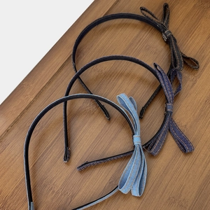 Three vintage denim bow headbands in various blue shades on a natural wooden background