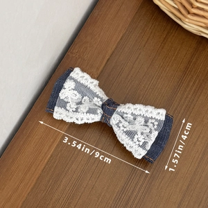 Detail van blauwe denim haarstrik met wit kant en 9cm afmeting op houten textuur