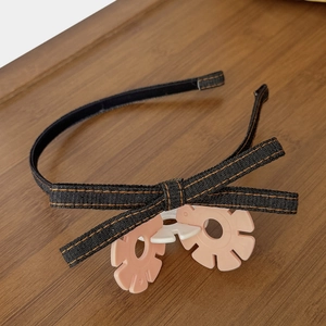 Close-up of dark denim bow headband with vintage orange contrast stitching detail