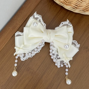 Détail du nœud à cheveux en satin blanc avec bordure en dentelle et pampilles en perles