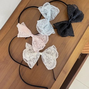 Set mit vier Spitzen-Haarreifen in Weiß Rosa Blau und Schwarz auf Holzuntergrund