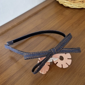 Detail shot of vintage denim bow headband with contrast orange stitching and pink floral clips