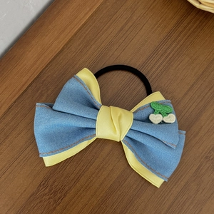 Détail d'une pince à cheveux avec nœud en denim et broderie cerise sur bois