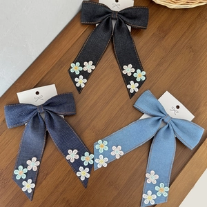 Vue détaillée de barrettes en denim avec broderies florales sur une table en bois