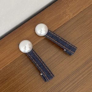 Macro-opname van twee denim haarclips met parels en gele stiksels op een houten tafel
