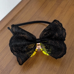 Nahaufnahme von elegantem Haarreif mit schwarzer Spitzenschleife und Blumenmuster auf Holz