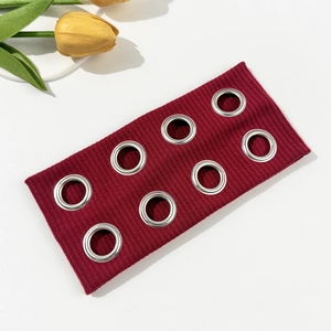Detail of burgundy ribbed headband with silver metal grommets and punk style texture