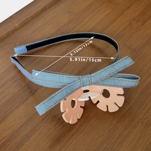 Vintage blue denim bow headband with pink floral accents on a wooden background