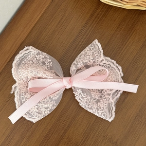 Detail of pink lace bow hair clip featuring delicate floral mesh and smooth satin ribbon