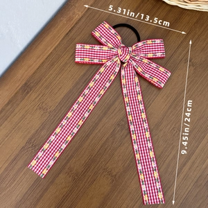 Détail du nœud vichy rouge avec fleurs et dimensions 13,5x24cm sur le ruban à cheveux