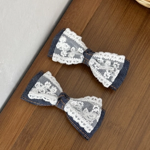 Detail van haarspelden met blauwe denim en witte kant met fijne oranje stiksels erop