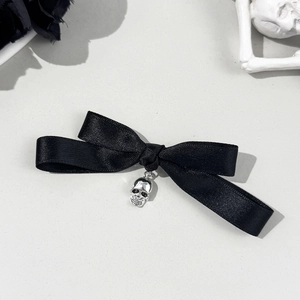 Détail d'une pince à cheveux nœud satin noir avec pendentif crâne de style gothique