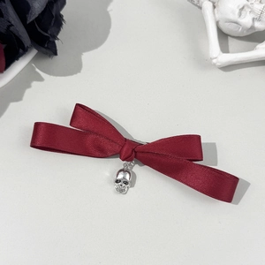 Détail du nœud en satin rouge foncé avec pendentif tête de mort gothique en métal argenté