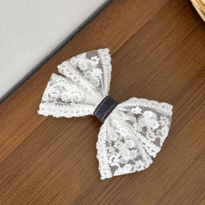 Detail van witte kant haarklem met blauwe denim kern en opvallende oranje stiksels erop