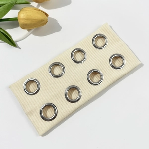 Detail of beige ribbed headband featuring double rows of metallic silver eyelets