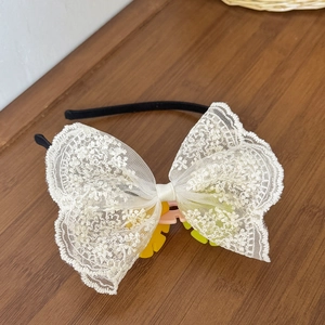 Detailansicht der großen cremefarbenen Spitzenschleife mit Blumenstickerei am Haarreif