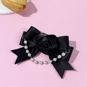 Detail view of black satin bow hair clip with fabric rose and white pearl tassel charms