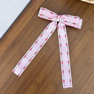 Détail d'un nœud à cheveux à carreaux roses avec broderies florales sur bois naturel