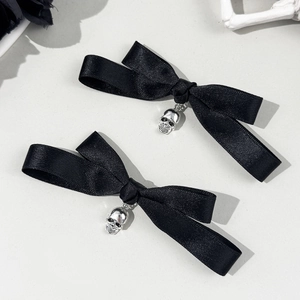 Détail de barrettes nœuds en satin noir avec pendentifs crâne argentés style gothique