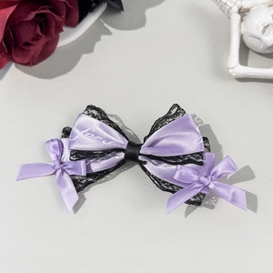 Macro detail of lavender satin bow hair clip with black lace trim and artistic font print