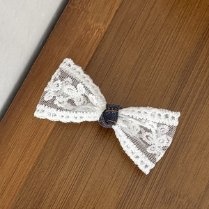 Detail van witte bloemen kant haarklem met donkerblauw gestippeld stoffen centrum
