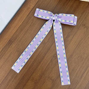 Détail du nœud papillon à carreaux violets avec de longs rubans fleuris sur fond de bois