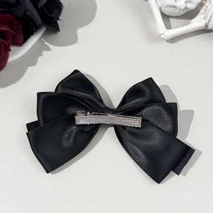 Gothic black satin ribbon hair bow with metal clip on dark aesthetic floral background