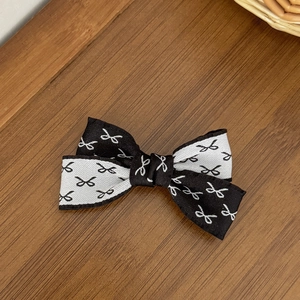 Détail du nœud à cheveux bicolore avec motifs mini nœuds sur fond en bois naturel