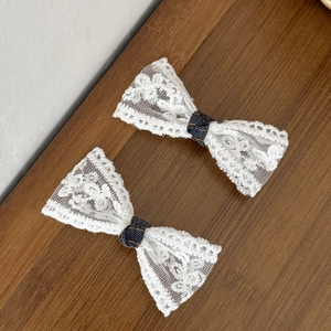 Detail van witte kanten haarspelden met marineblauwe polkadots op houten tafel