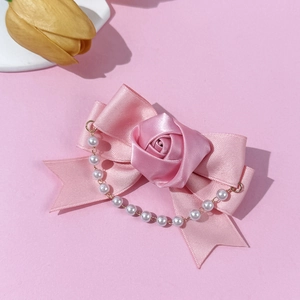 Detail of pink satin bow hair clip with fabric rose and pearl tassel on soft background