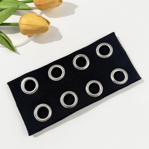 Detail of black knit headband featuring eight symmetrical silver metal eyelets in punk style