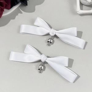 Détail de barrettes nœuds blancs avec crânes argentés pour un style punk gothique
